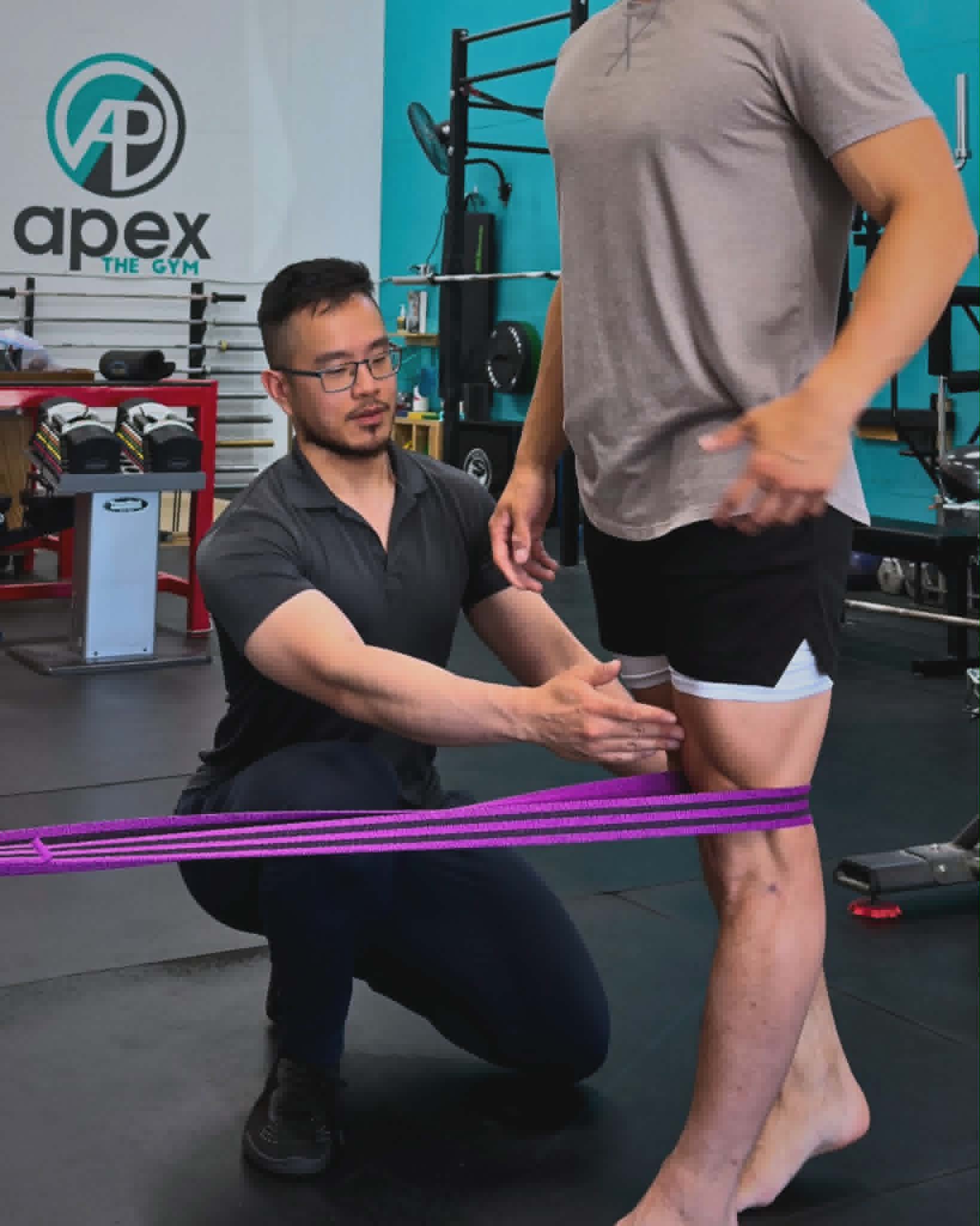 Pat Wu guiding a knee rehabilitation exercise with a resistance band